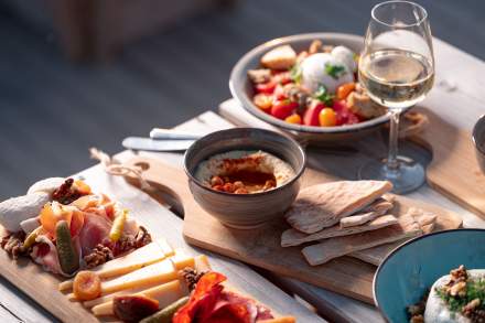 Apéritif au coucher du soleil avec planche et verres de vin blanc sur la plage