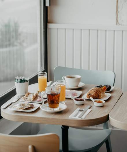 Petit-déjeuner servi près de la fenêtre avec jus d’orange, café et viennoiseries